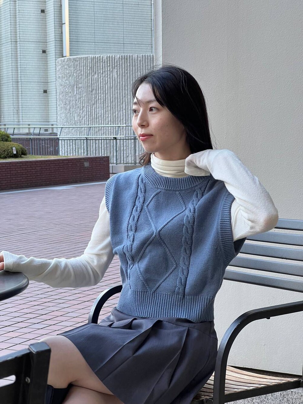 ブルー系のベスト、ブラック系のブーツ、ベージュ系のTシャツ/カットソーを着用したレディースの冬コーディネートの7枚目の写真