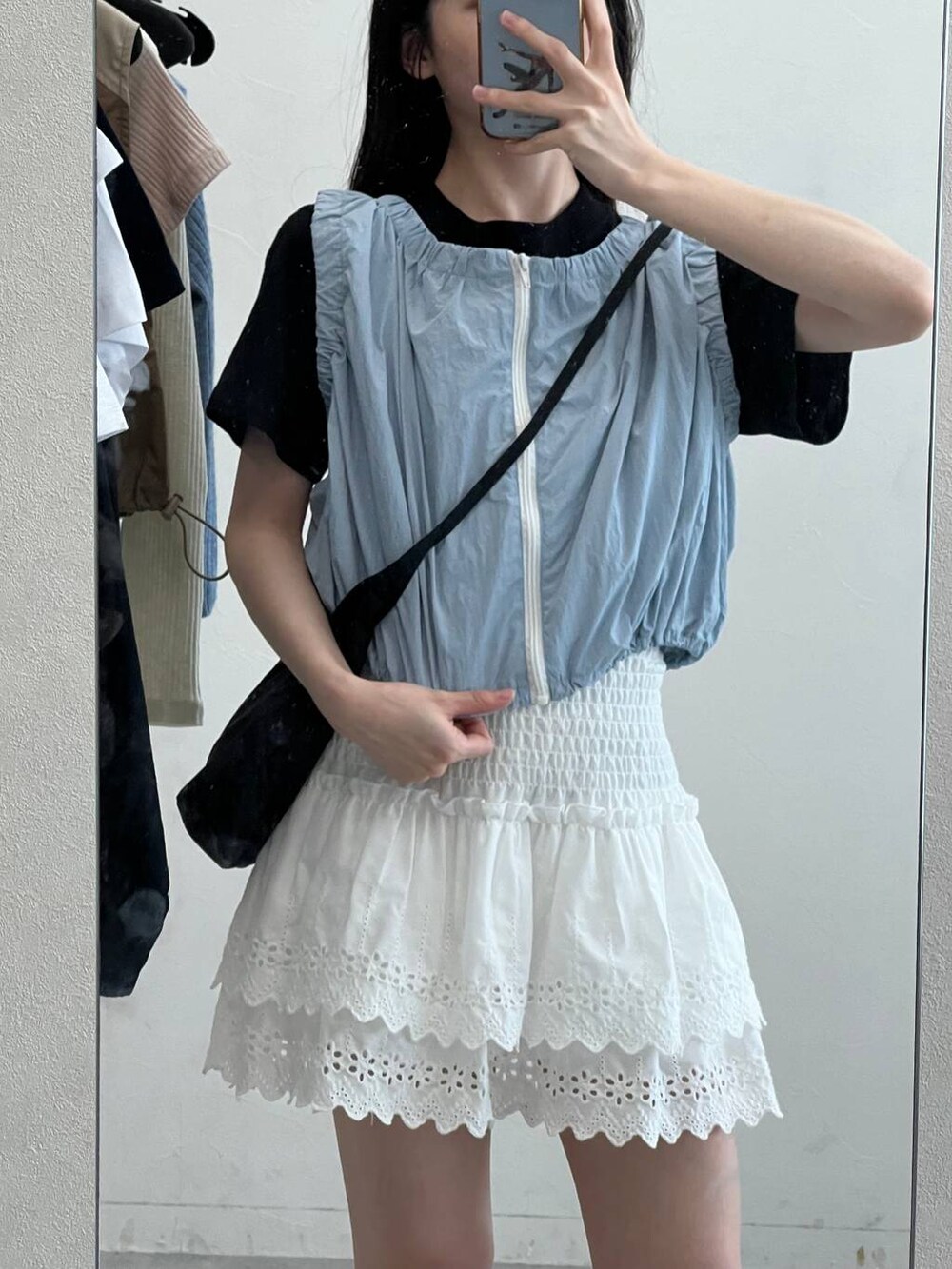 ブルー系のベスト、ホワイト系のスカート、ブラック系のショルダーバッグを着用したレディースの夏コーディネートの7枚目の写真