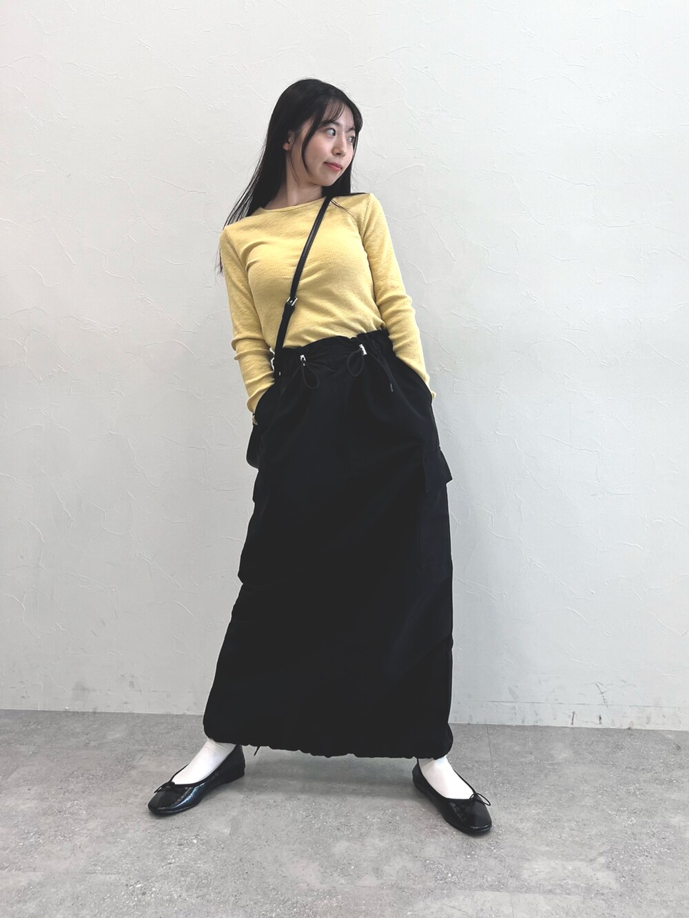 イエロー系のTシャツ/カットソー、ブラック系のショルダーバッグ、ブラック系のスカートを着用したレディースの秋コーディネートの3枚目の写真
