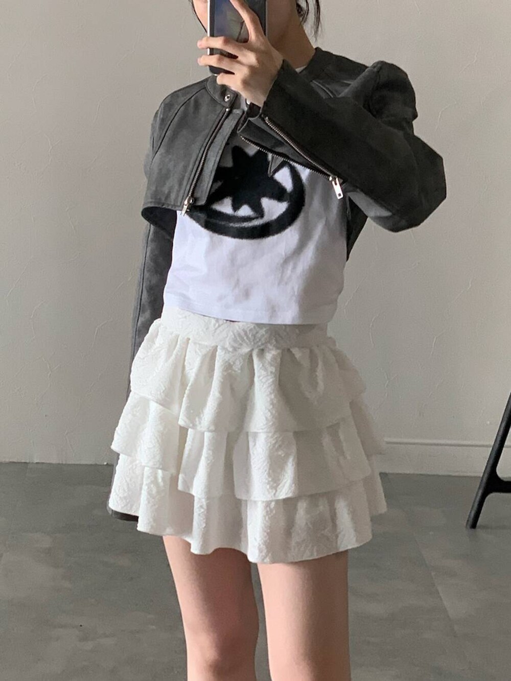 グレー系のライダースジャケット、ホワイト系のスカート、ホワイト系のTシャツ/カットソーを着用したレディースの秋コーディネートの4枚目の写真