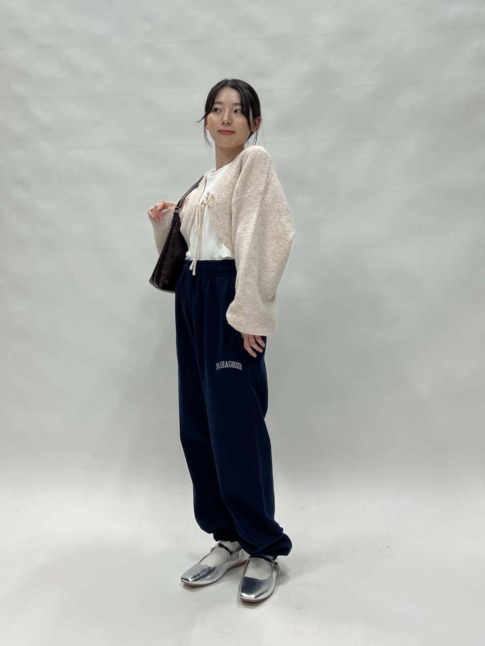 ブラック系のスウェットパンツ、ピンク系のカーディガン/ボレロ、ブラウン系のバッグを着用したレディースの冬コーディネートの3枚目の写真