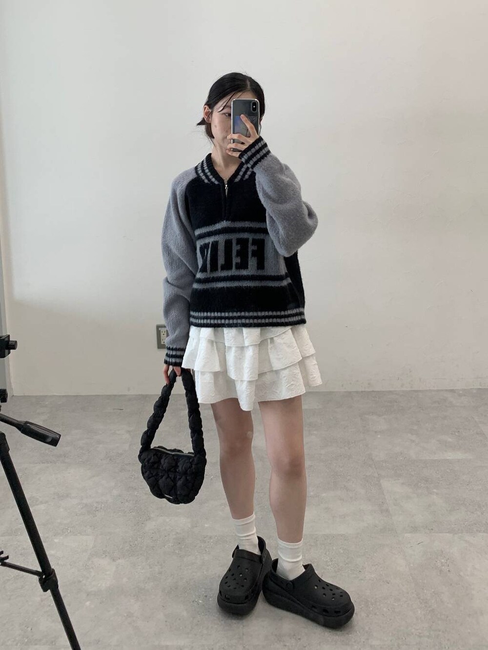 ブラック系のサンダル、ブラック系のショルダーバッグ、ホワイト系のスカートを着用したレディースの秋コーディネートの3枚目の写真