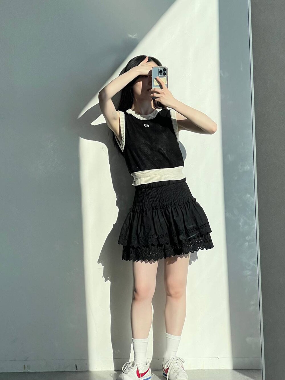 ブラック系のスカート、ブラック系のベスト、ベージュ系のショルダーバッグを着用したレディースの春コーディネートの9枚目の写真