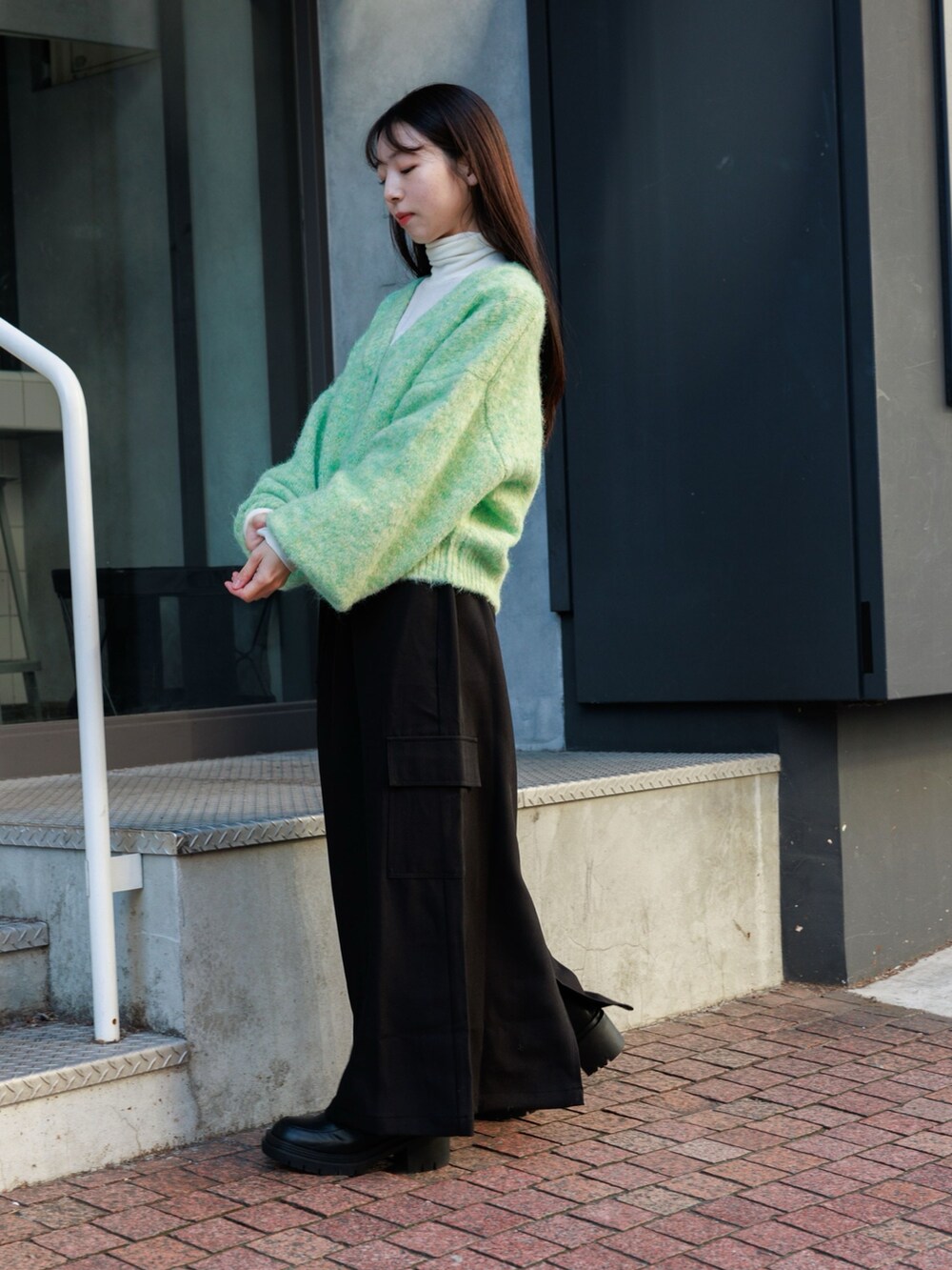 ブラック系のブーツ、ブラック系のスカート、グリーン系のカーディガン/ボレロを着用したレディースの冬コーディネートの3枚目の写真