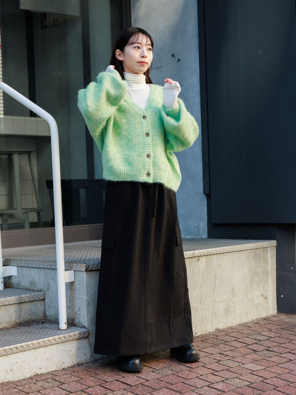 ブラック系のブーツ、ブラック系のスカート、グリーン系のカーディガン/ボレロを着用したレディースの冬コーディネートの2枚目の写真