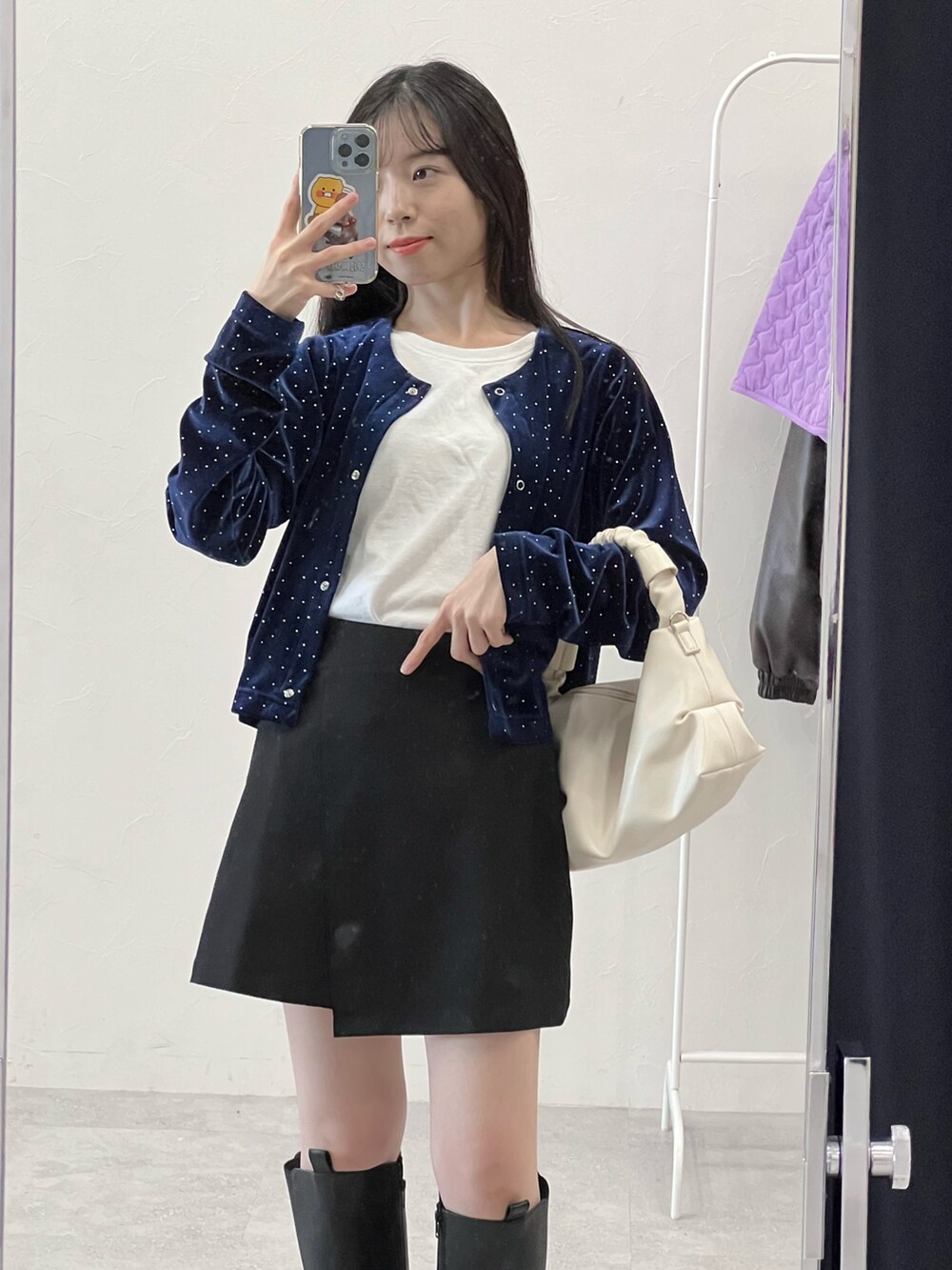 ブラック系のブーツ、ブラック系のスカート、ベージュ系のショルダーバッグを着用したレディースの冬コーディネートの3枚目の写真