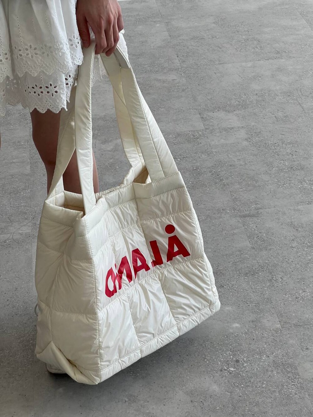 ホワイト系のスカート、ホワイト系のボストンバッグ、グレー系のTシャツ/カットソーを着用したレディースの夏コーディネートの7枚目の写真