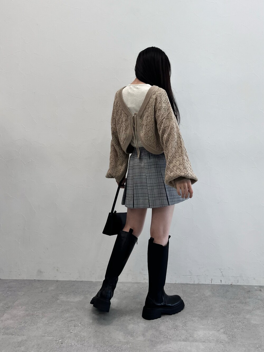 ブラック系のブーツ、ブラック系のショルダーバッグ、グレー系のスカートを着用したレディースの冬コーディネートの3枚目の写真