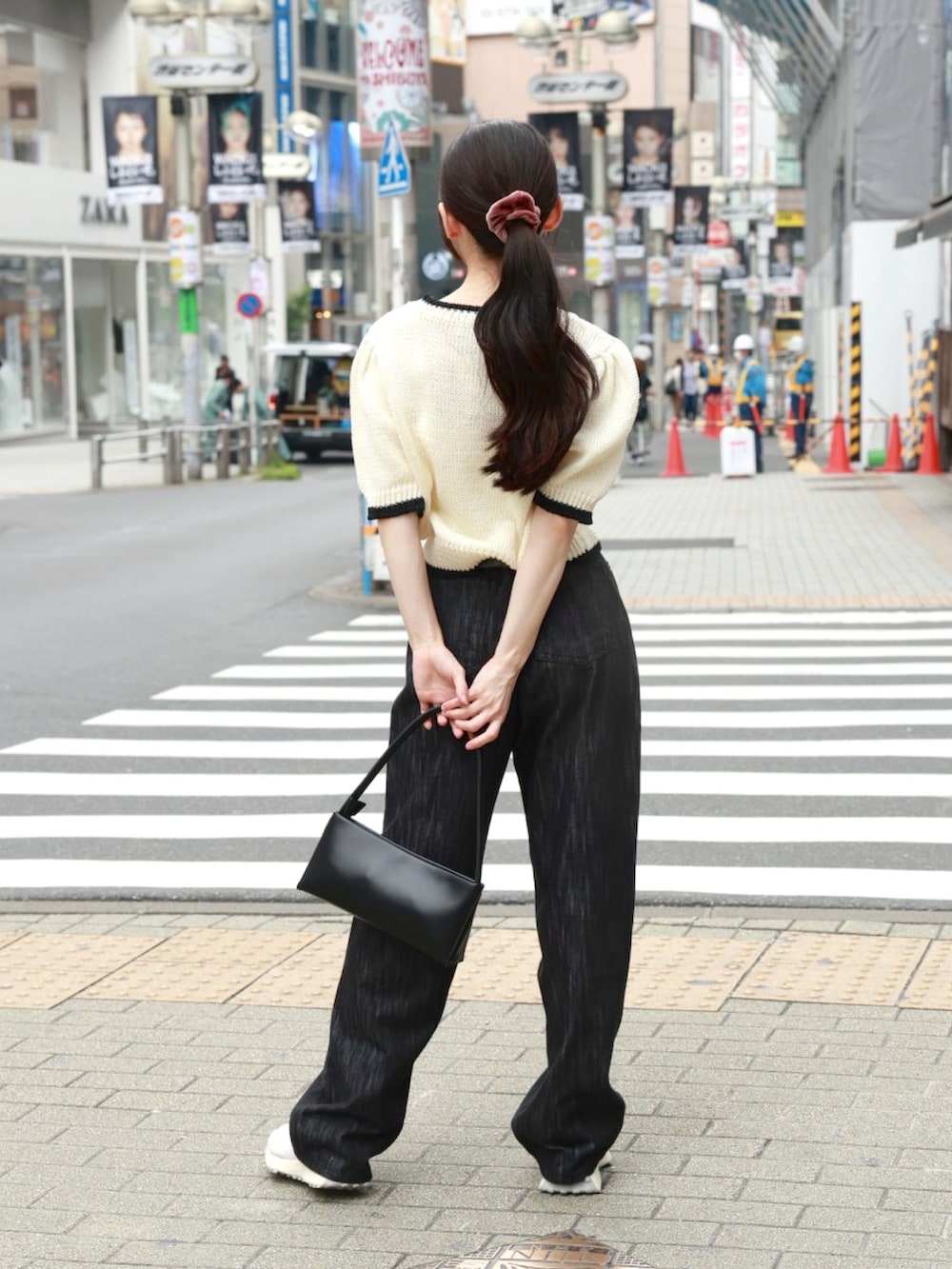 ベージュ系のニット/セーター、ブラック系のショルダーバッグ、ブラック系のデニムパンツを着用したレディースの夏コーディネートの3枚目の写真