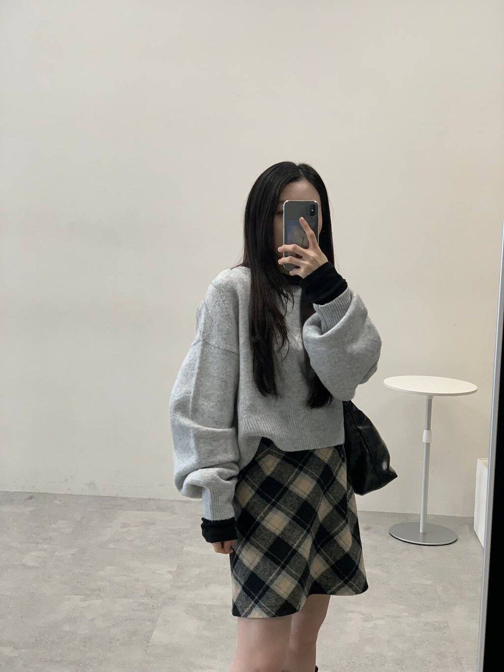 グレー系のニット/セーター、ブラック系のスカート、ブラック系のハンドバッグを着用したレディースの秋コーディネートの6枚目の写真