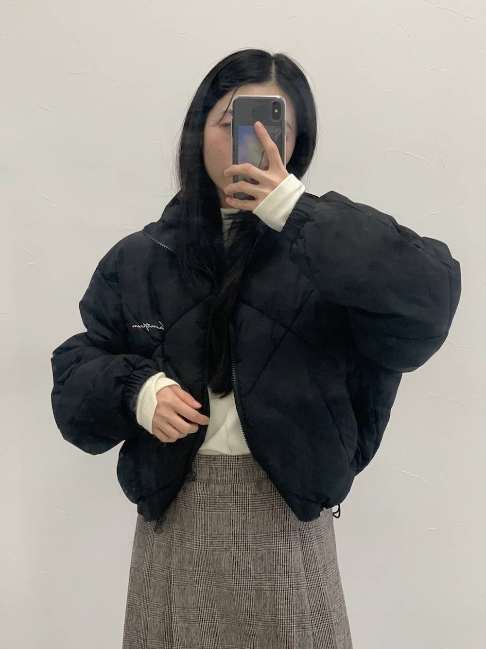 ブラウン系のスカート、ベージュ系のTシャツ/カットソー、ブラック系のダウンジャケット/コートを着用したレディースの冬コーディネートの7枚目の写真