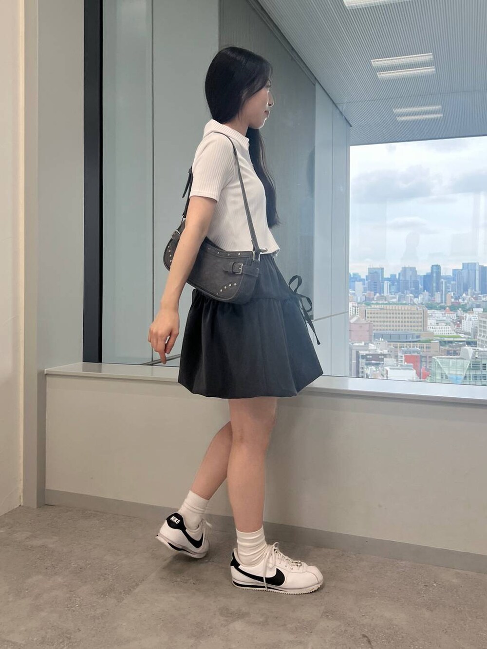 グレー系のスカート、ブラック系のトートバッグ、ホワイト系のカーディガン/ボレロを着用したレディースの夏コーディネートの3枚目の写真