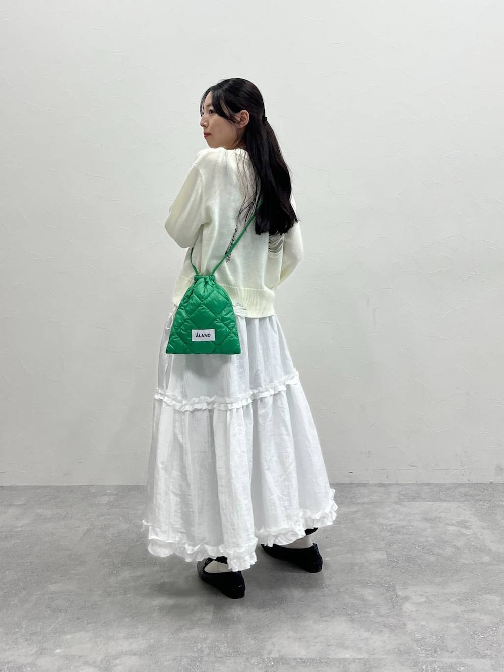 ホワイト系のニット/セーター、グリーン系のショルダーバッグ、ブラック系のスウェットパンツを着用したレディースの春コーディネートの4枚目の写真