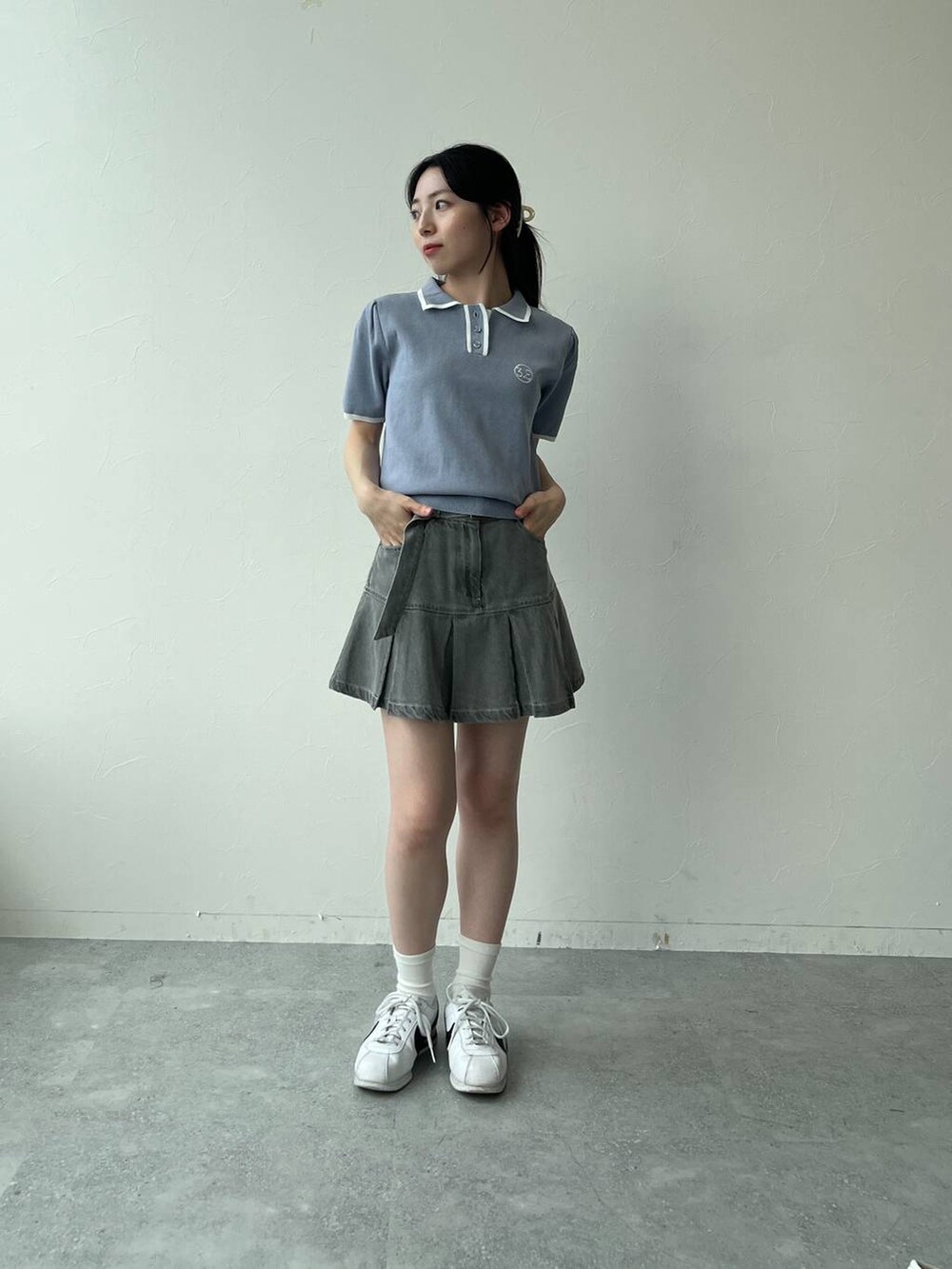 ブルー系のニット/セーター、グレー系のデニムスカートを着用したレディースの夏コーディネートの3枚目の写真