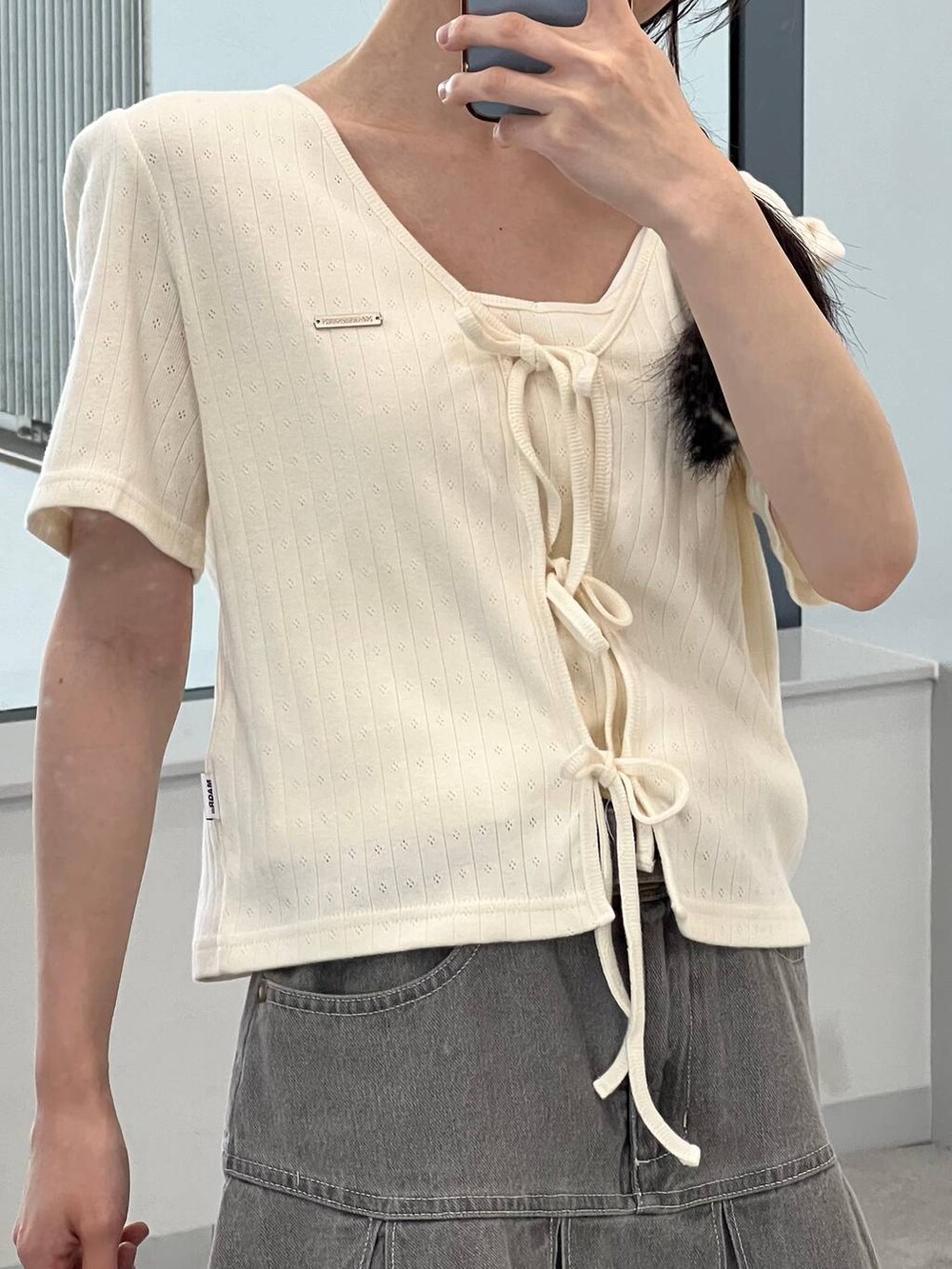 ベージュ系のカーディガン/ボレロ、グレー系のデニムスカートを着用したレディースの夏コーディネートの7枚目の写真