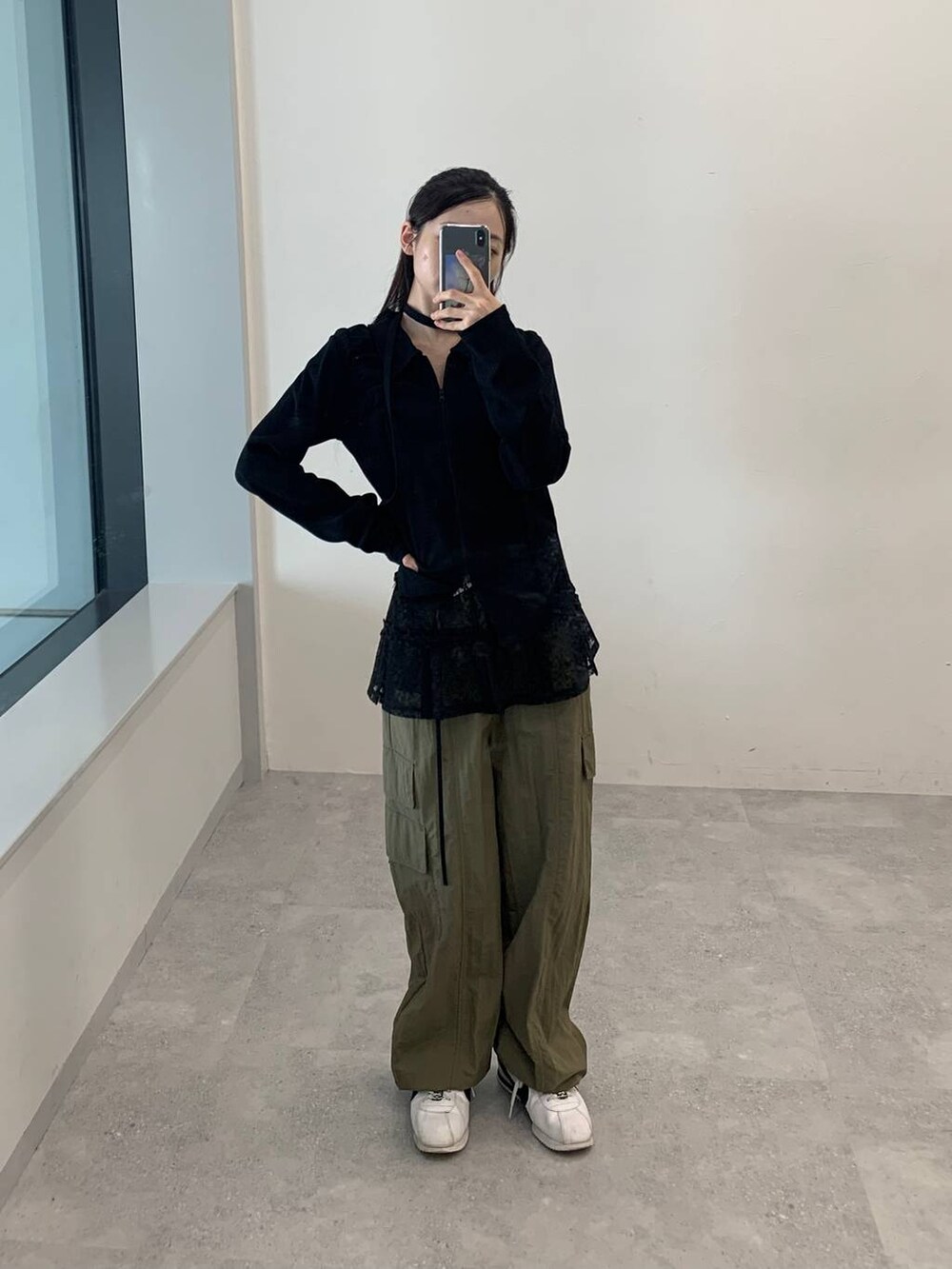 グリーン系のカーゴパンツ、ブラック系のスカート、ブラック系のTシャツ/カットソーを着用したレディースの秋コーディネートの3枚目の写真