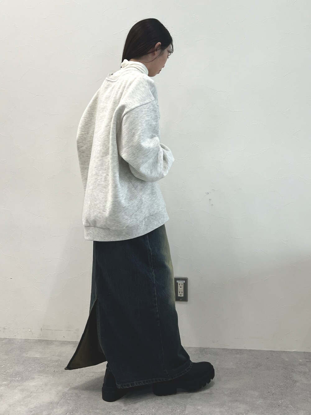 ブラック系のブーツ、ブルー系のデニムスカート、ベージュ系のTシャツ/カットソーを着用したレディースの冬コーディネートの3枚目の写真