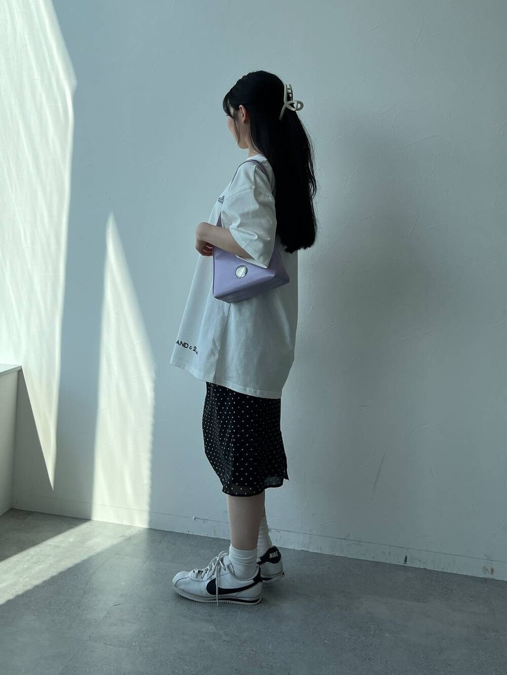ブラック系のスカート、パープル系のハンドバッグ、ホワイト系のTシャツ/カットソーを着用したレディースの夏コーディネートの4枚目の写真
