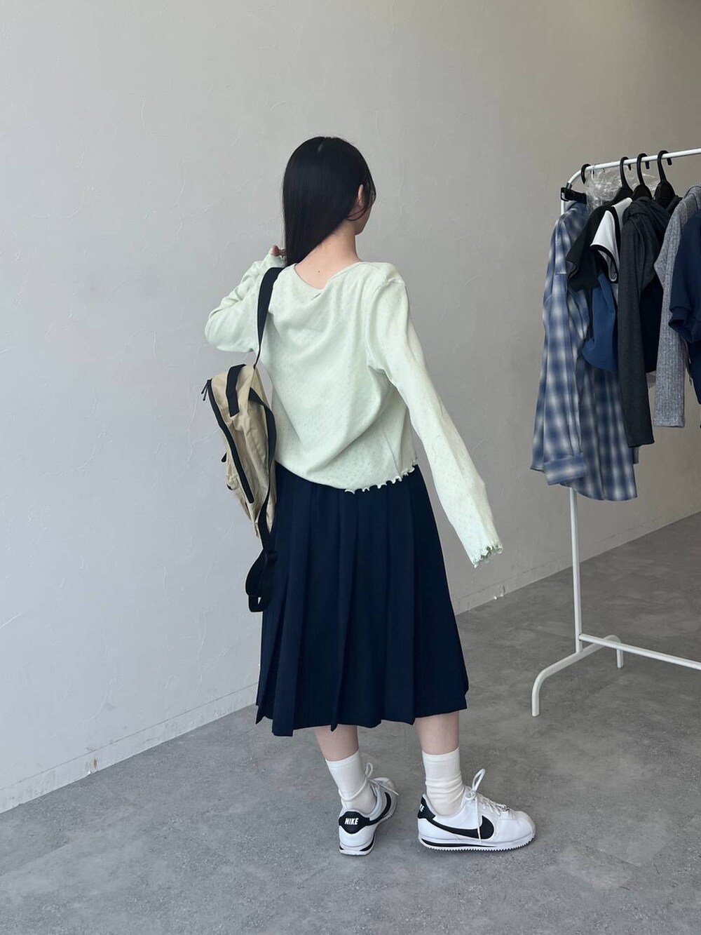 ベージュ系のバックパック/リュック、ブルー系のスカート、グリーン系のカーディガン/ボレロを着用したレディースの春コーディネートの5枚目の写真