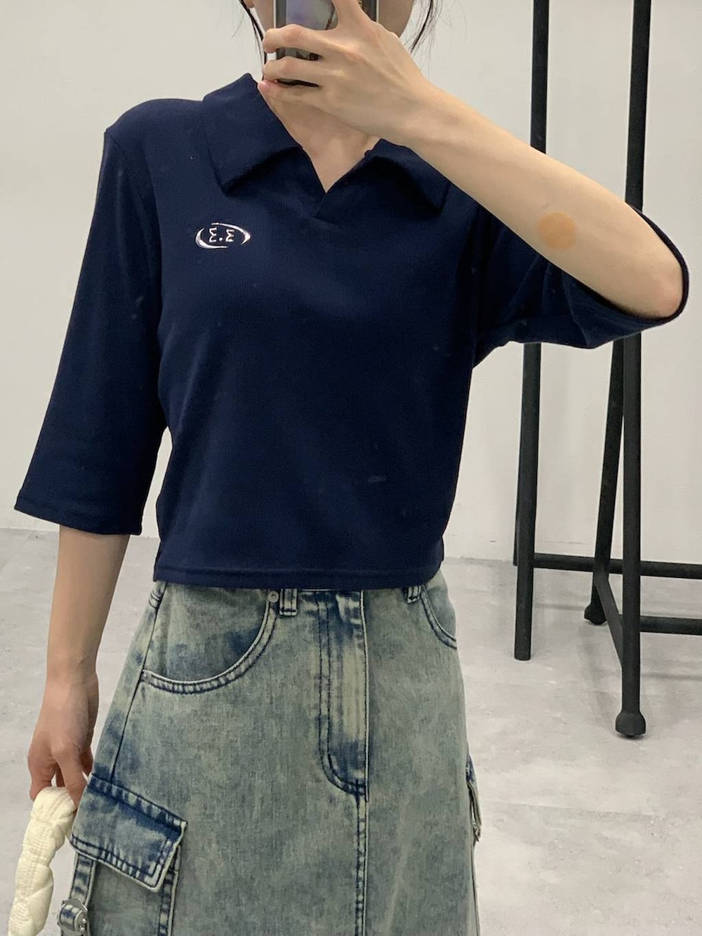 ブルー系のデニムスカート、ホワイト系のショルダーバッグ、ブルー系のTシャツ/カットソーを着用したレディースの秋コーディネートの3枚目の写真