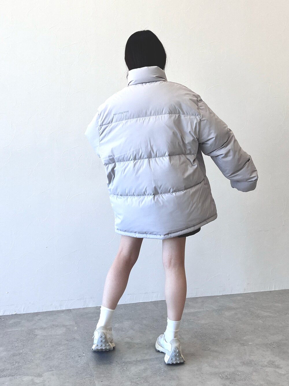 グレー系のダウンジャケット/コート、グリーン系のスカート、ホワイト系のスニーカーを着用したレディースの冬コーディネートの2枚目の写真