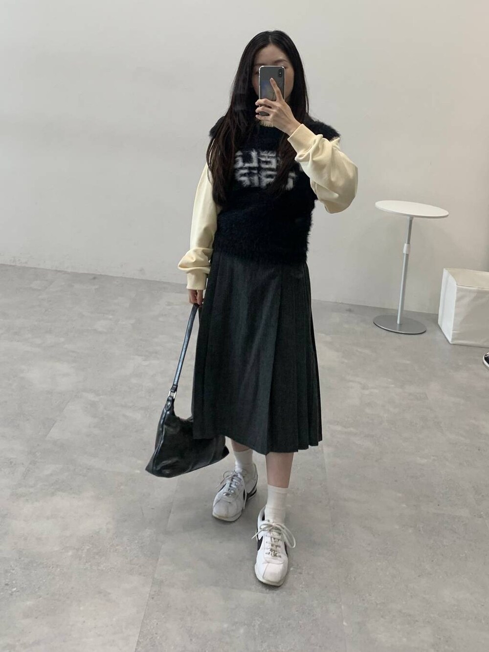 ベージュ系のスウェット、グレー系のスカート、ブラック系のハンドバッグを着用したレディースの冬コーディネートの4枚目の写真