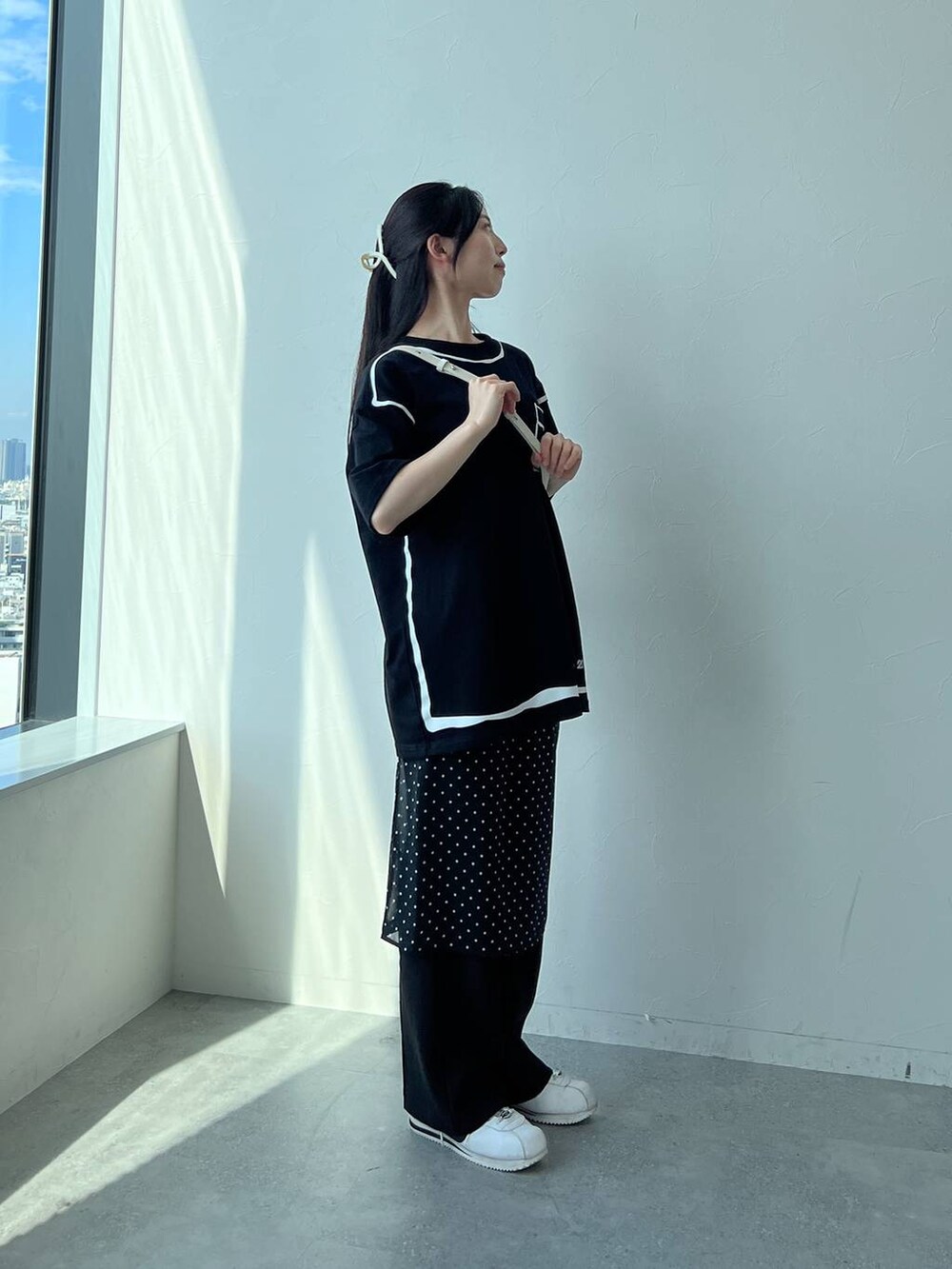 ホワイト系のハンドバッグ、ブラック系のスカートを着用したレディースの夏コーディネートの2枚目の写真