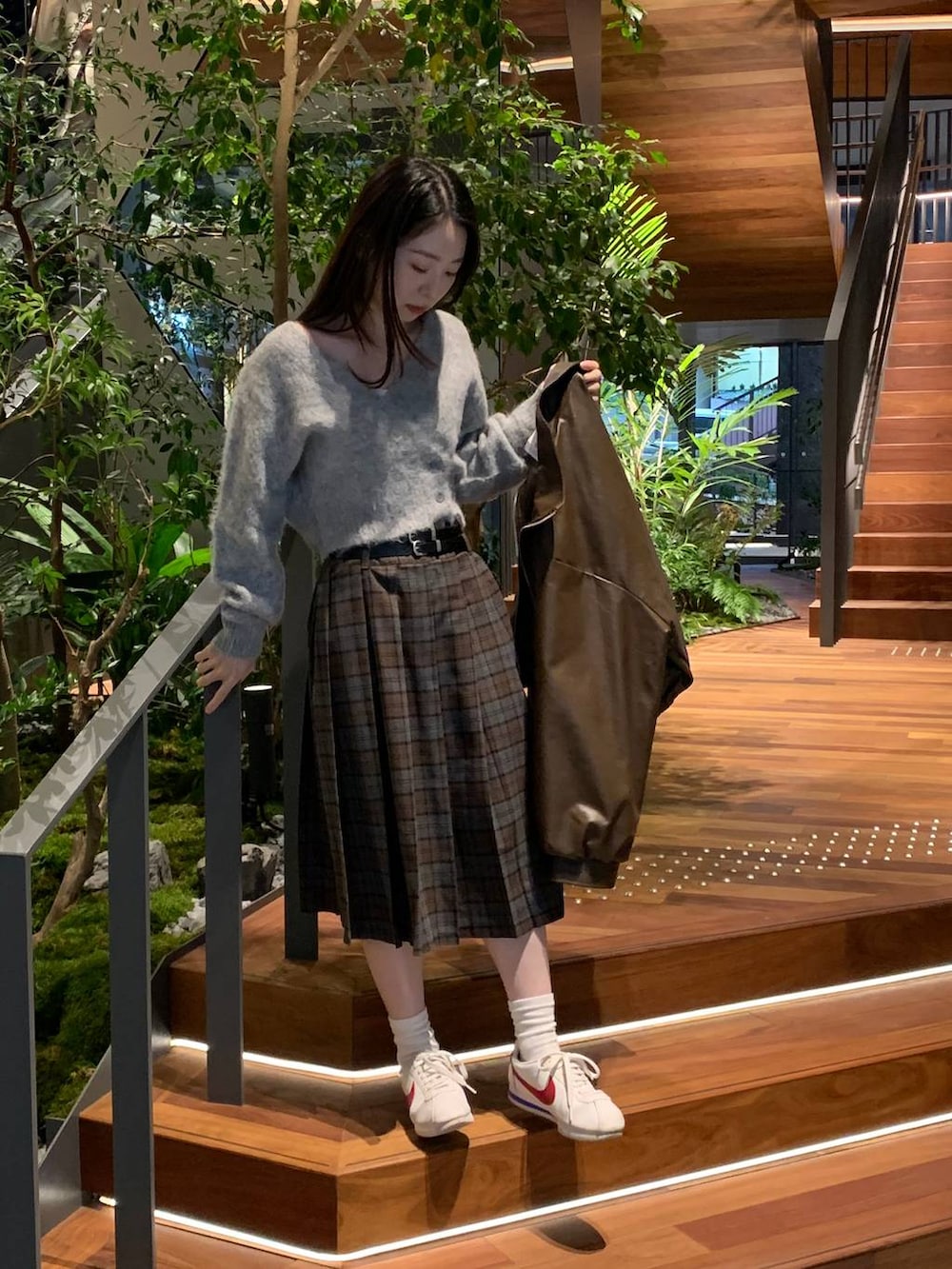 グレー系のカーディガン/ボレロ、ブラウン系のブルゾン、ブラウン系のスカートを着用したレディースの秋コーディネートの2枚目の写真