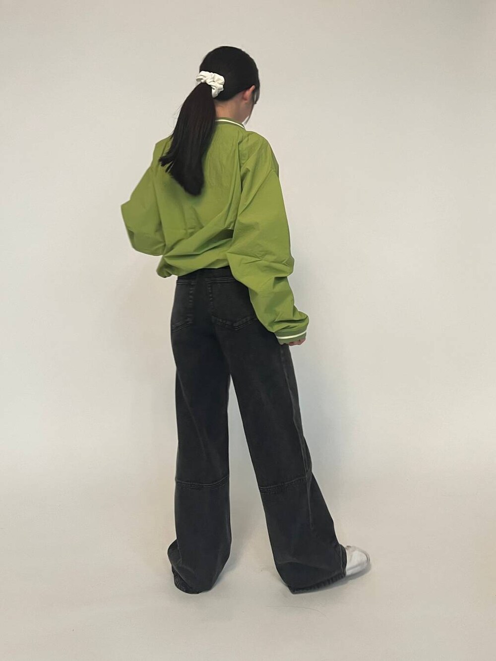 グリーン系のTシャツ/カットソー、ホワイト系のスニーカー、ブラック系のデニムパンツを着用したレディースの冬コーディネートの3枚目の写真