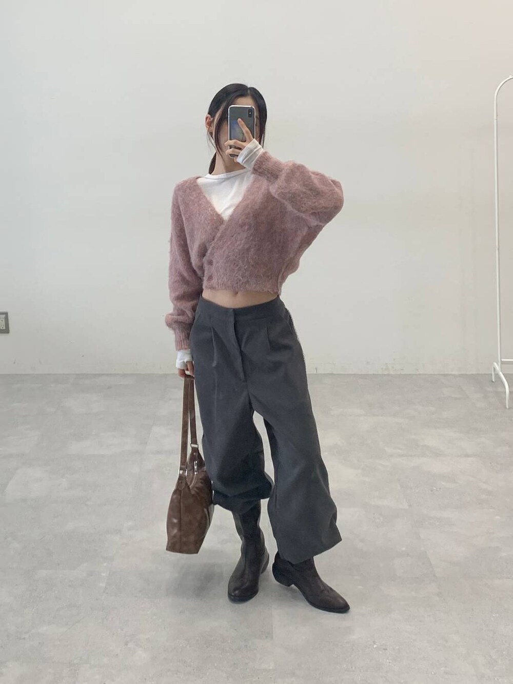 オレンジ系のカーディガン/ボレロ、グレー系のスラックス、ベージュ系のTシャツ/カットソーを着用したレディースの秋コーディネートの4枚目の写真