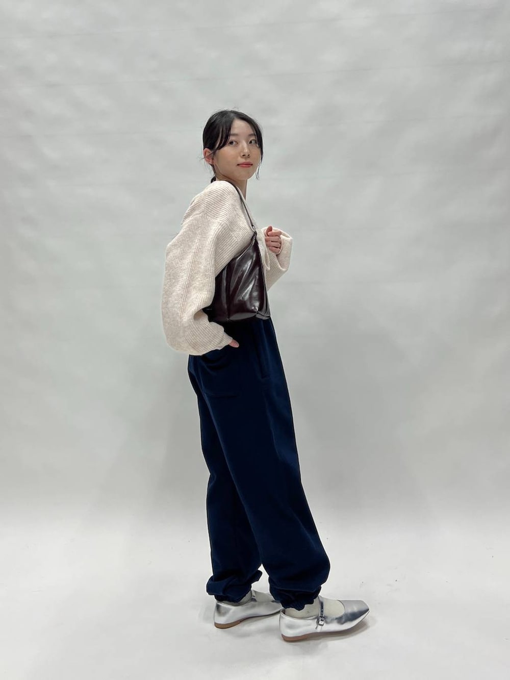 ブラック系のスウェットパンツ、ピンク系のカーディガン/ボレロ、ブラウン系のバッグを着用したレディースの冬コーディネートの6枚目の写真