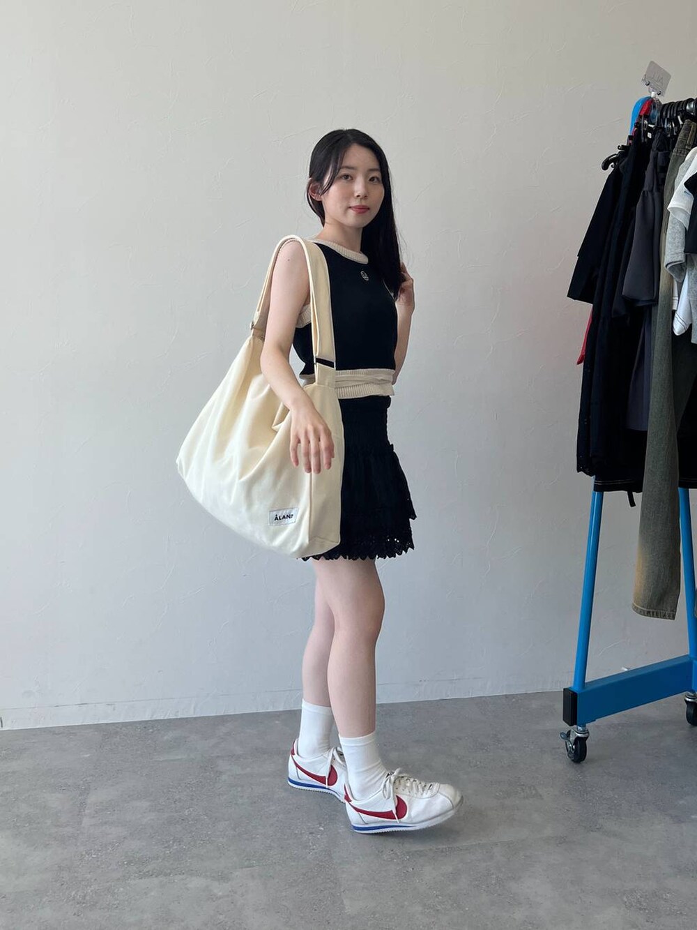 ブラック系のスカート、ブラック系のベスト、ベージュ系のショルダーバッグを着用したレディースの春コーディネートの5枚目の写真