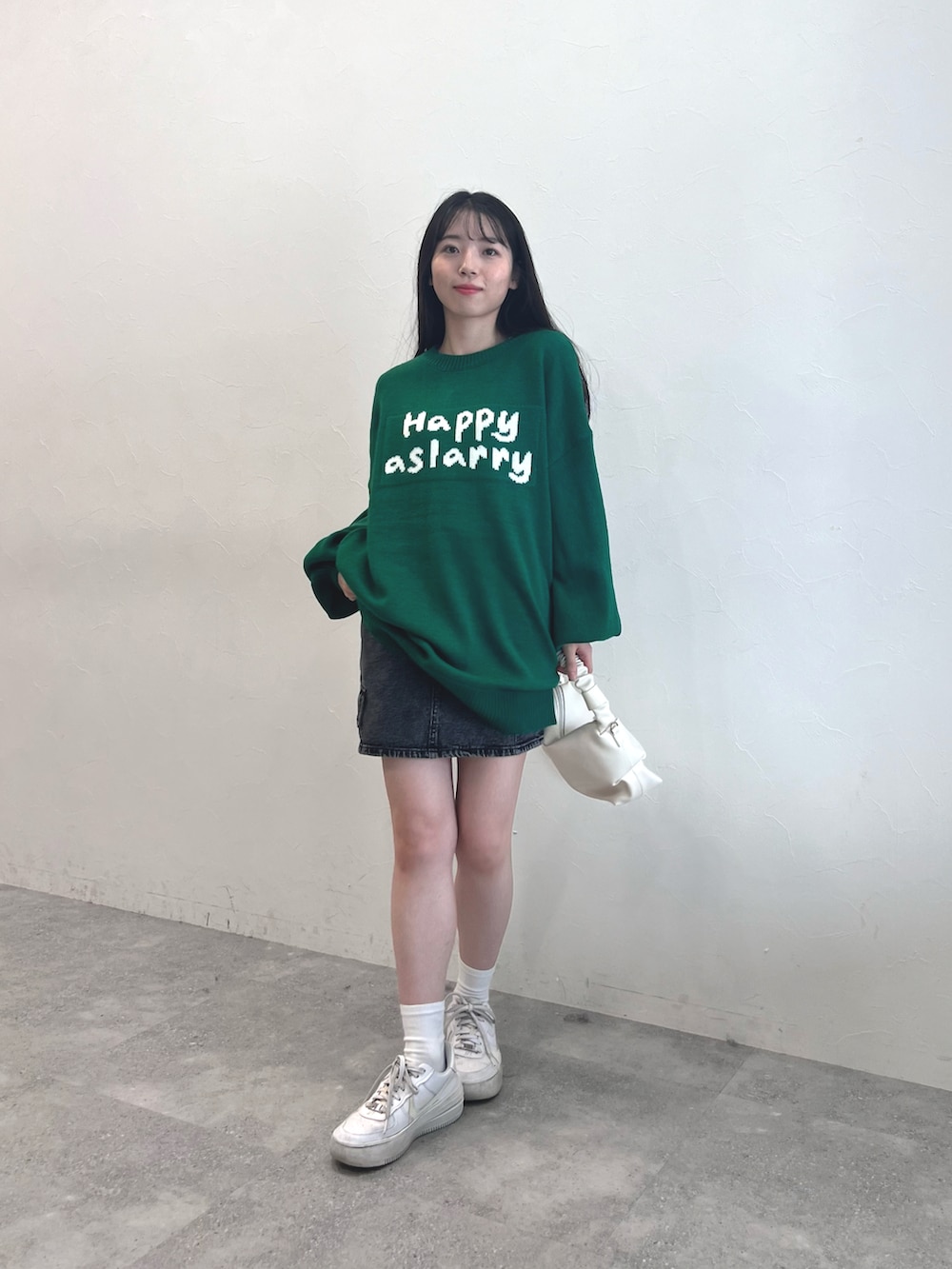 ホワイト系のスニーカー、ブラック系のスカート、グリーン系のニット/セーターを着用したレディースの秋コーディネートの2枚目の写真