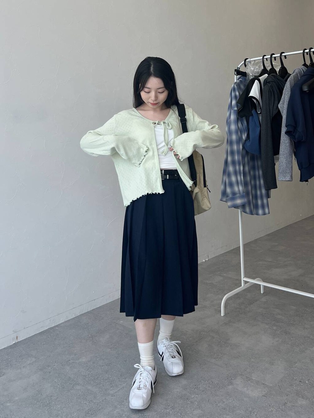 ベージュ系のバックパック/リュック、ブルー系のスカート、グリーン系のカーディガン/ボレロを着用したレディースの春コーディネートの2枚目の写真