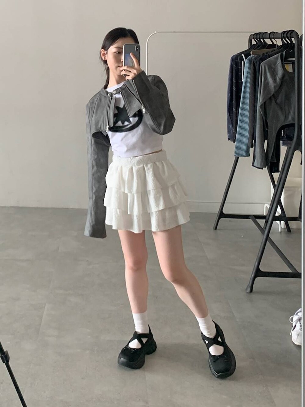 グレー系のライダースジャケット、ホワイト系のスカート、ホワイト系のTシャツ/カットソーを着用したレディースの秋コーディネートの3枚目の写真