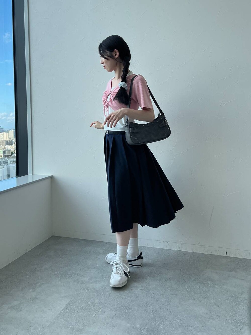 ブルー系のスカート、ブラック系のトートバッグ、ピンク系のカーディガン/ボレロを着用したレディースの夏コーディネートの2枚目の写真