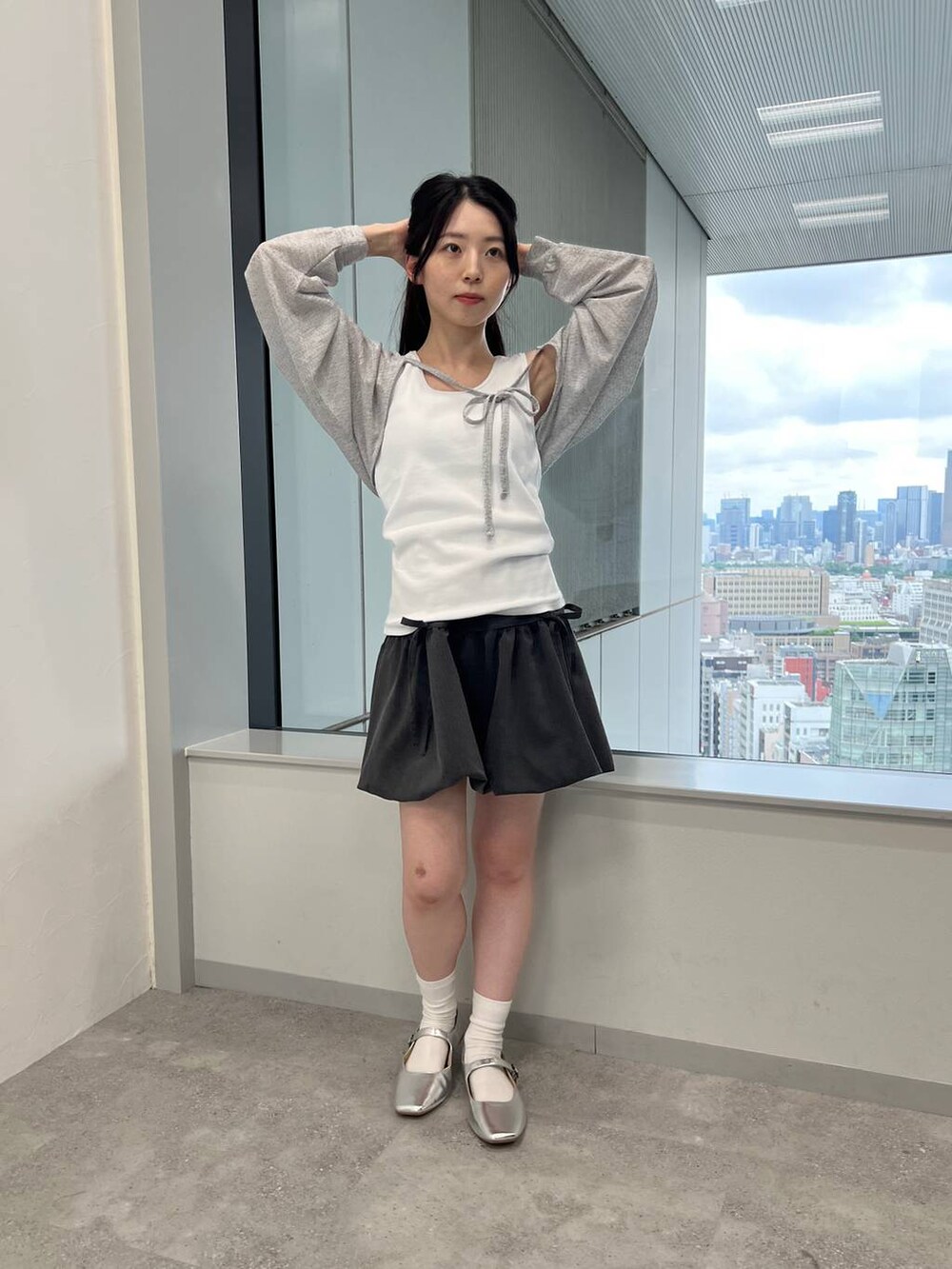 グレー系のスカート、ホワイト系のタンクトップ、グレー系のカーディガン/ボレロを着用したレディースの夏コーディネートの2枚目の写真