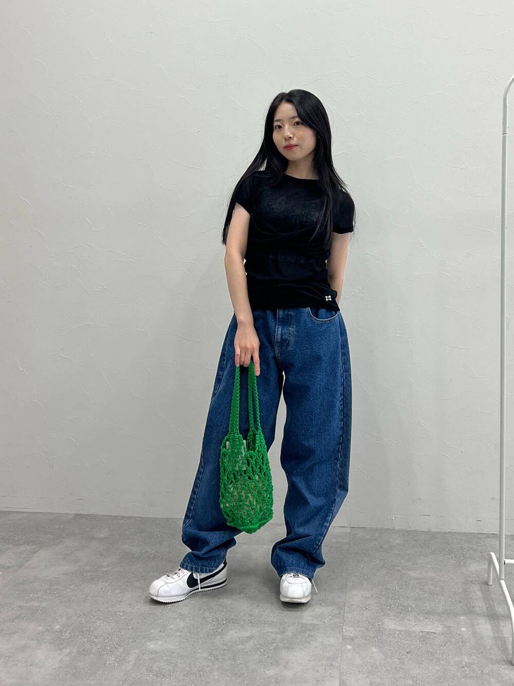 グリーン系のトートバッグ、ブルー系のデニムパンツ、ブラック系のTシャツ/カットソーを着用したレディースの夏コーディネートの4枚目の写真