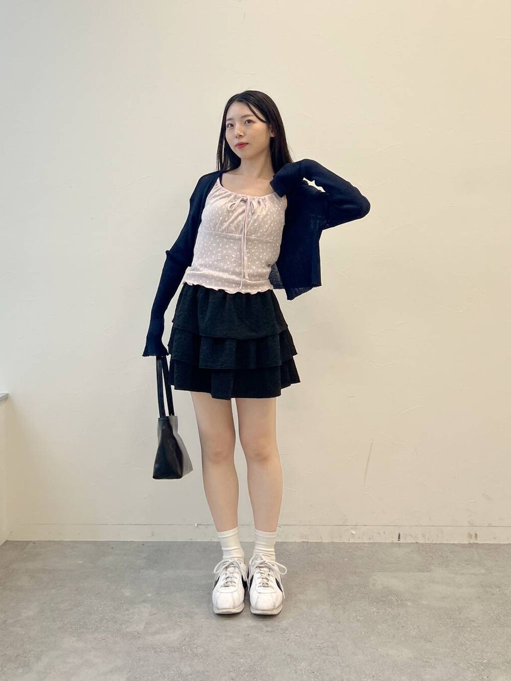 ピンク系のキャミソール、ブラック系のハンドバッグ、ブラック系のスカートを着用したレディースの夏コーディネートの3枚目の写真