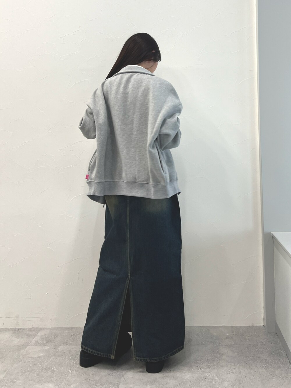 ブラック系のブーツ、ブルー系のデニムスカート、ベージュ系のTシャツ/カットソーを着用したレディースの冬コーディネートの3枚目の写真