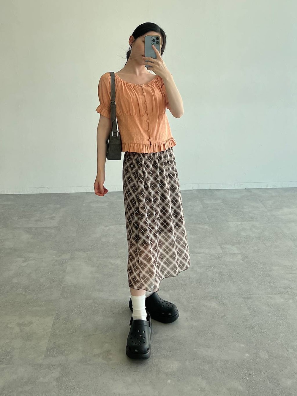 ブラック系のサンダル、オレンジ系のシャツ/ブラウス、ブラック系のトートバッグを着用したレディースの夏コーディネートの2枚目の写真