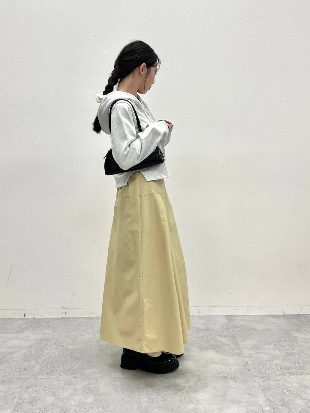 グレー系のスウェット、ベージュ系のスカート、ブラック系のハンドバッグを着用したレディースの冬コーディネートの5枚目の写真