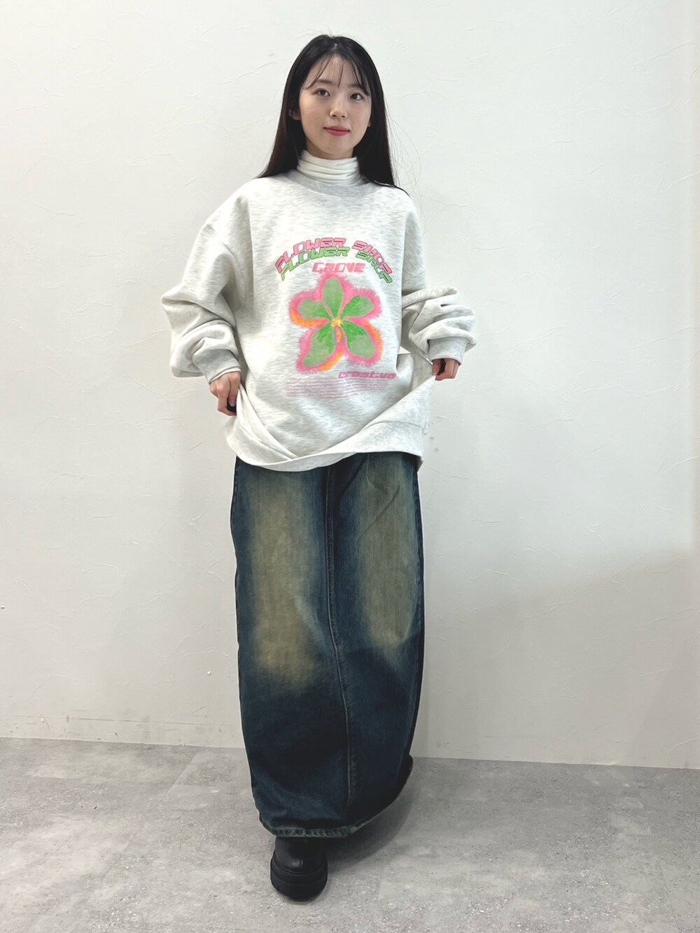 ブラック系のブーツ、ブルー系のデニムスカート、ベージュ系のTシャツ/カットソーを着用したレディースの冬コーディネートの2枚目の写真