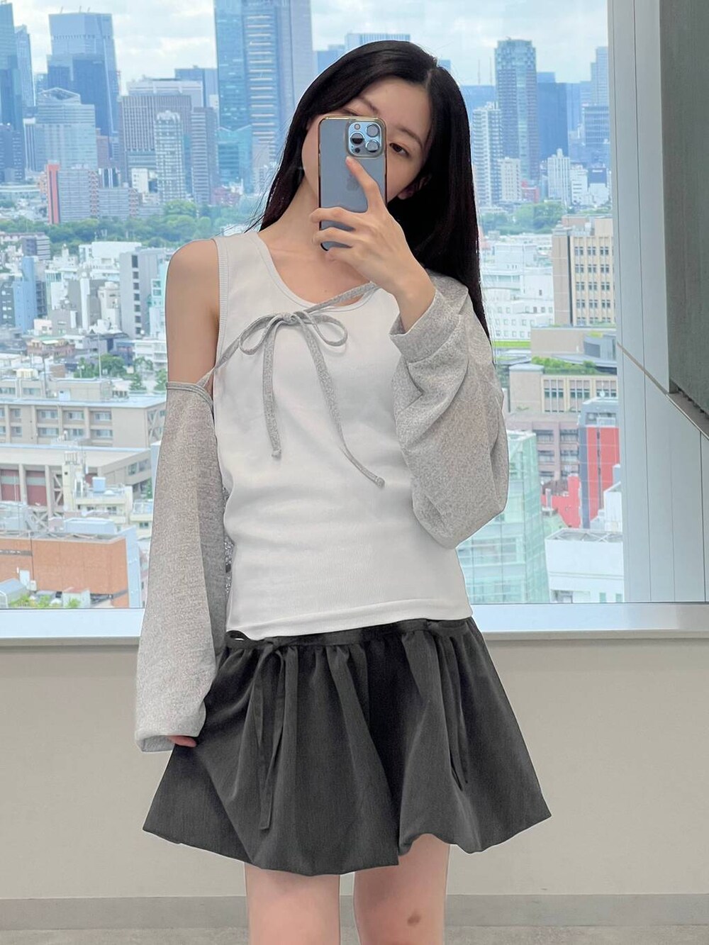 グレー系のスカート、ホワイト系のタンクトップ、グレー系のカーディガン/ボレロを着用したレディースの夏コーディネートの5枚目の写真