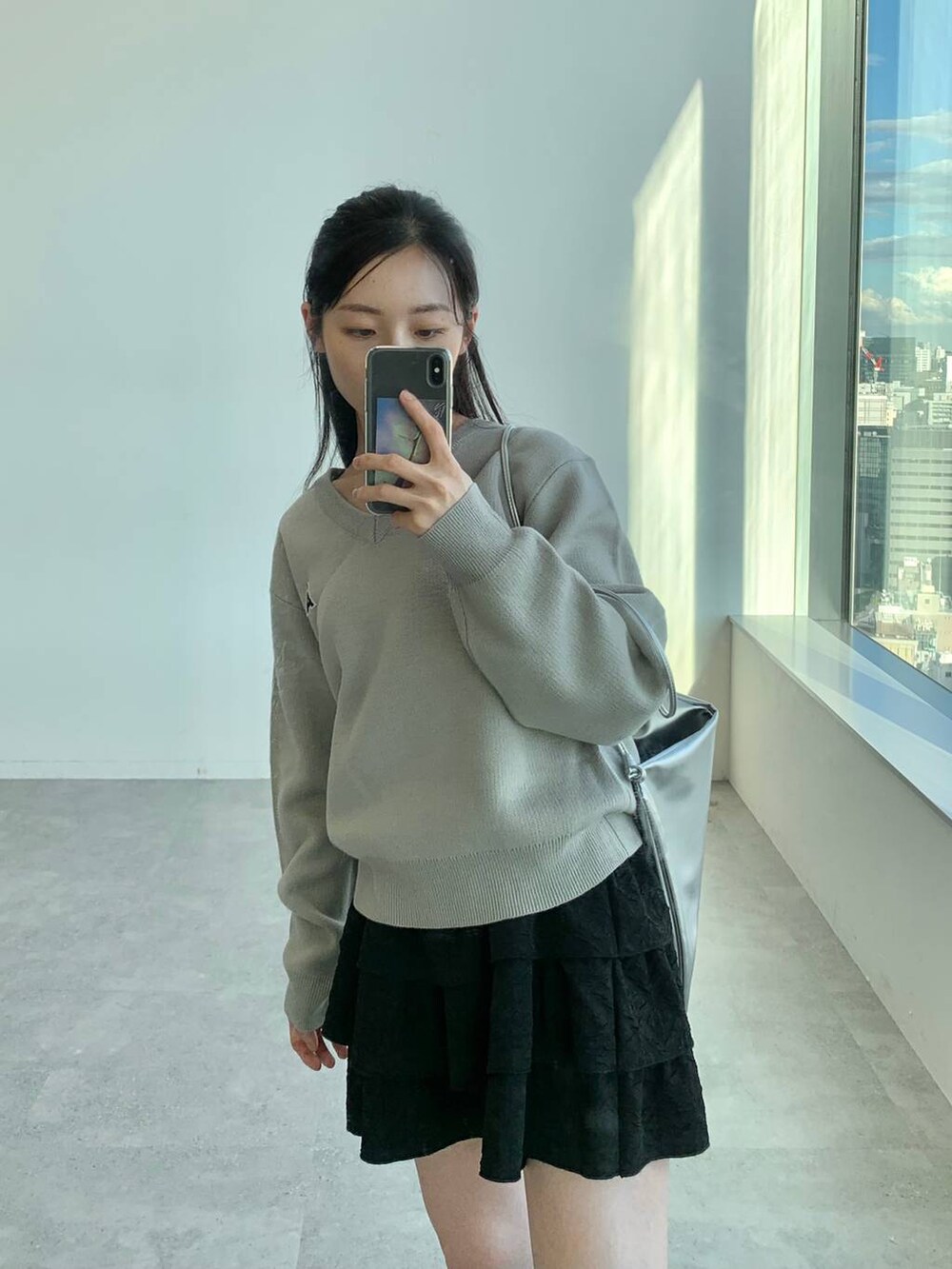 ブラック系のスカート、グレー系のバックパック/リュック、グレー系のニット/セーターを着用したレディースの秋コーディネートの6枚目の写真