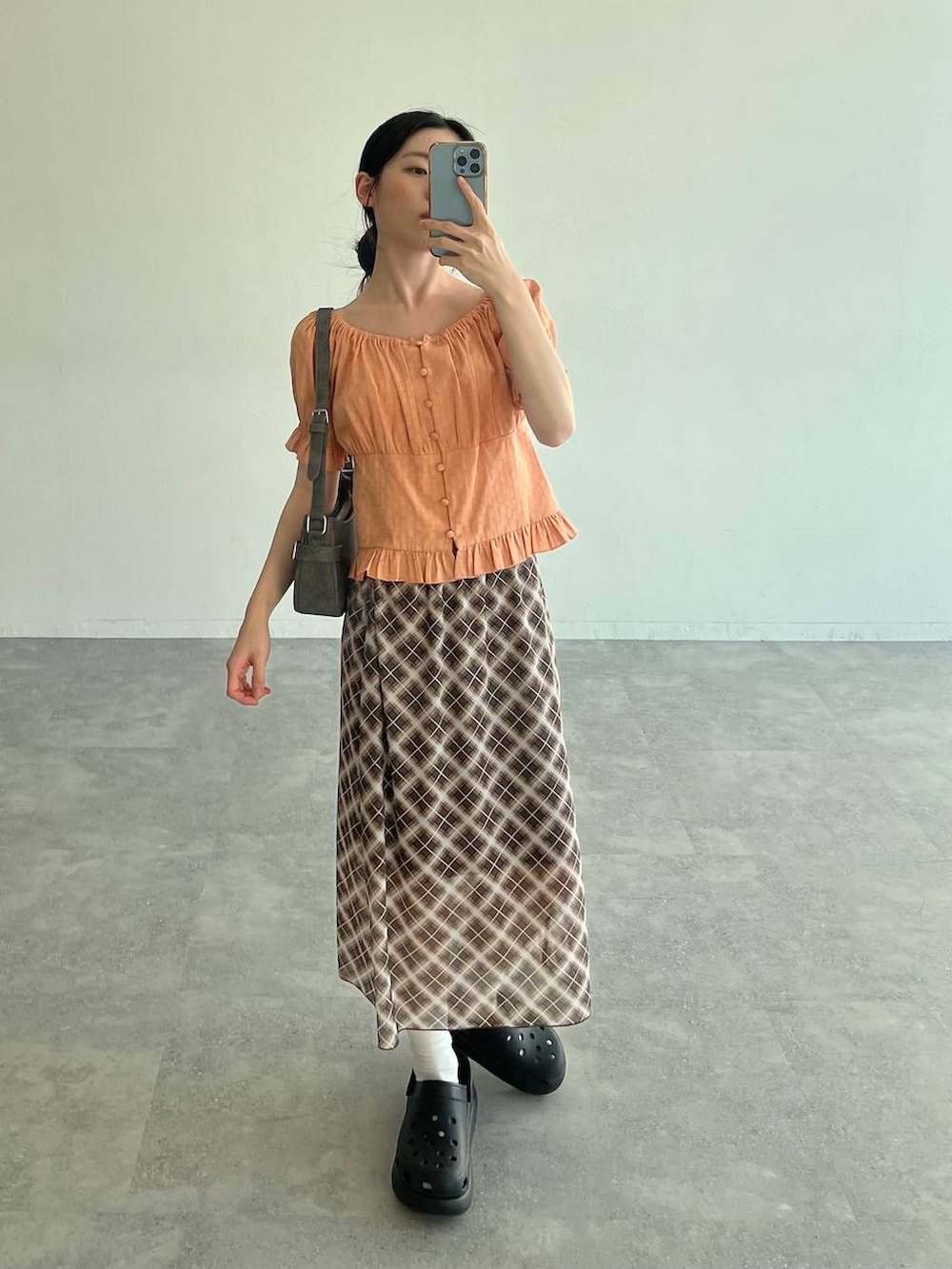 ブラック系のサンダル、オレンジ系のシャツ/ブラウス、ブラック系のトートバッグを着用したレディースの夏コーディネートの3枚目の写真