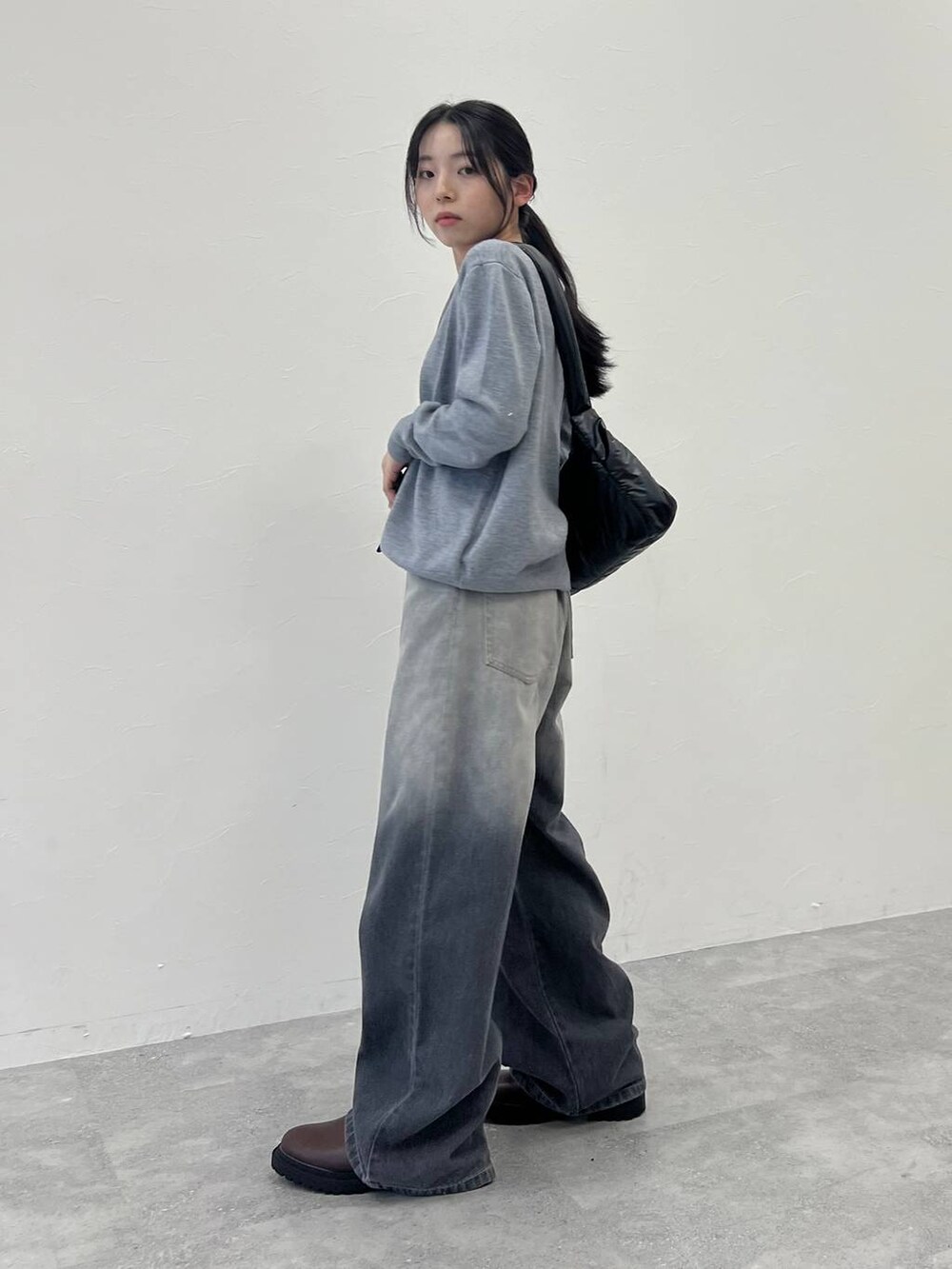 ブラック系のショルダーバッグ、ブラック系のデニムパンツ、グレー系のカーディガン/ボレロを着用したレディースの冬コーディネートの3枚目の写真