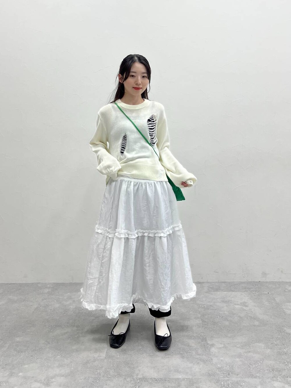 ホワイト系のニット/セーター、グリーン系のショルダーバッグ、ブラック系のスウェットパンツを着用したレディースの春コーディネートの2枚目の写真