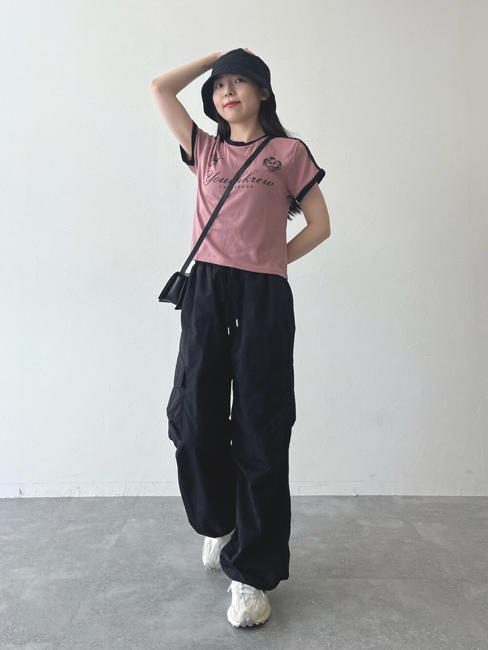 ピンク系のTシャツ/カットソー、ブラック系のショルダーバッグ、ブラック系のカーゴパンツを着用したレディースの夏コーディネートの2枚目の写真