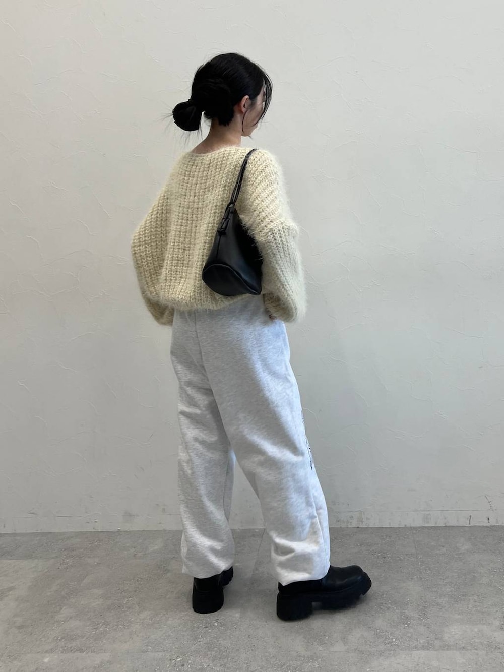 ブラック系のブーツ、ブラック系のショルダーバッグ、ベージュ系のニット/セーターを着用したレディースの冬コーディネートの4枚目の写真